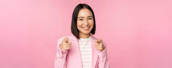 <strong>恭喜</strong>微笑热情的朝鲜文企业夫人女商人指出手指相机祝贺赞扬站粉红色的背景