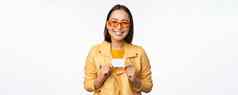 肖像美丽的现代亚洲女孩太阳镜微笑快乐显示信贷卡站白色背景