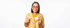 肖像美丽的现代亚洲女孩太阳镜微笑快乐显示信贷卡站白色背景