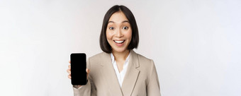 图像亚洲<strong>企业</strong>女人显示应用程序接口移动电话屏幕使惊讶脸表达式哇站白色背景