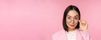 肖像亚洲女商人眼镜感兴趣相机微笑专业女售货员盯着感兴趣粉红色的背景