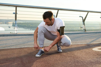 高加索人运动员运动员跑步者系鞋带站跑步机城市玻璃城市桥准备好了早....慢跑