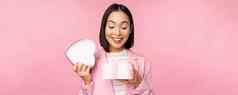 快乐可爱的朝鲜文女孩西装打开心形状的盒子浪漫的礼物白色一天假期站西装粉红色的背景