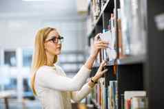 书拍摄集中年轻的女人采取书读书架上内部图书馆