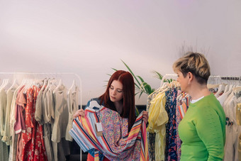 年轻的女人客户建议买衣服女售货员专家衣服时尚商店购物概念
