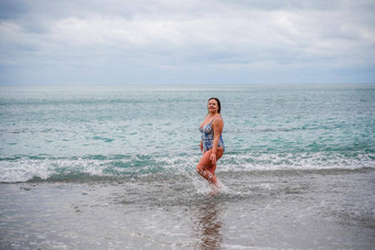 丰满女人洗澡西装进入水冲浪海滩灰色的天空<strong>云游</strong>泳冬天