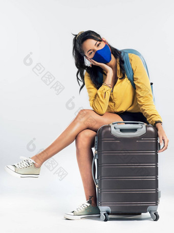 采取预防措施保护旅行拍摄年轻的女人穿面具坐着手提箱