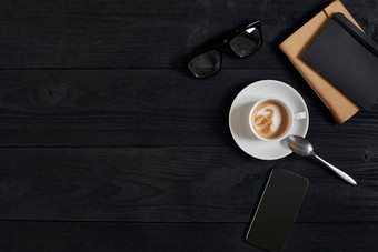 视图聪明的电话笔记本杯拿铁咖啡黑色的木背景