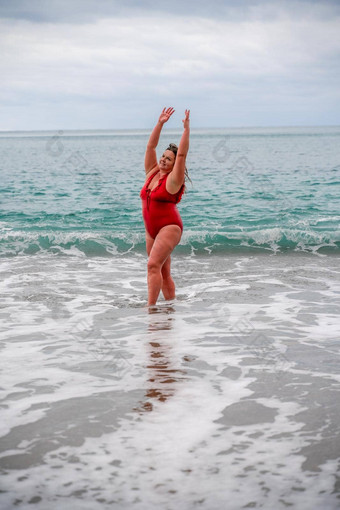 女人洗澡西装海脂肪年轻的女人红色的泳衣进入水冲浪
