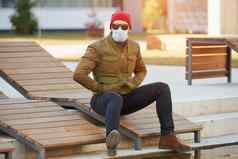 的家伙坐着木甲板椅子穿太阳镜脸面具病毒