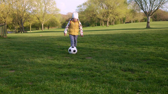 快乐家庭孩子们有趣的春天公园孩子运行孩子女孩运球黑色的白色经典足球球绿色草人玩足球童年体育运动冠军概念