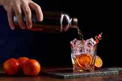 酒精鸡尾酒倒瓶gless橙色皮冰石头桌子上
