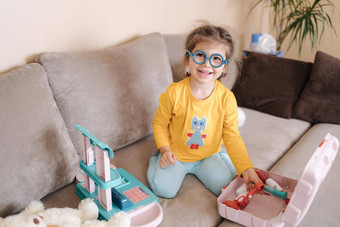 可爱的女孩微笑玩医生房间可爱的一年女孩花时间玩女孩穿眼镜黄色的上衣蓝色的紧身裤乌克兰可爱的孩子