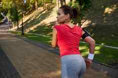 后视图女运动员慢跑者运行城市公园跑步机享受户外锻炼健身功能培训温暖的阳光明媚的夏天一天