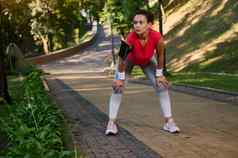 女跑步者拉美裔女运动员休息城市公园感觉疲惫慢跑跑步机温暖的阳光明媚的夏天一天身体重量培训减肥节食概念