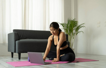 亚洲女人移动PC电脑瑜伽工作室健身技术健康的生活方式概念
