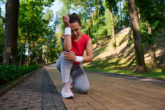 疲惫女运动员女跑步者感觉疼痛膝盖运行路径森林公园体育受伤膝盖疼痛体育运动概念