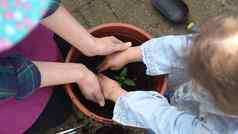 快乐学前教育女孩孩子女儿穿作品手套腐殖质靴子种植花能花园孩子帮助妈妈。家庭自然加德林环境春天夏天概念
