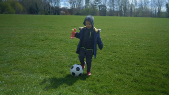 快乐家庭孩子们有趣的春天公园孩子运行孩子男孩运球黑色的白色经典足球球绿色草人玩足球童年体育运动冠军概念