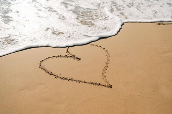 男孩黄色的橡胶靴子画心形状沙子海滩学校孩子触碰水秋天冬天海孩子有趣的波海岸春天假期假期概念