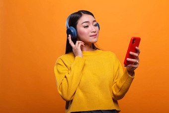 放松友好的可爱的亚洲女人听音乐音频流媒体<strong>平台智能</strong>手机设备