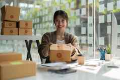 年轻的亚洲女人持有包裹盒子交付物流服务小业务企业家锻造分布仓库概念小老板首页办公室在线市场营销产品主题