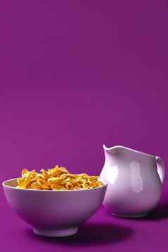 碗玉米片壶牛奶紫色的背景oncept健康的早餐