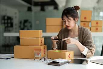 年轻的亚洲女商人老板包装照片纸板盒子年轻的老板女人开始业务在线人在线购物锻造企业家自由工作概念