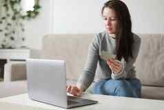 年轻的女人持有信贷卡移动PC首页支付在线首页购物互联网银行电子商店概念