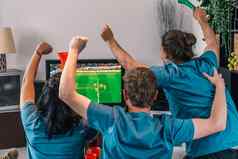 足球风扇朋友庆祝胜利首页年轻的人看足球电视休闲概念