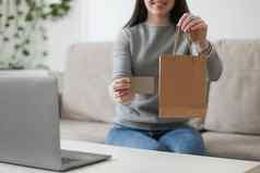 年轻的女人持有信贷卡移动PC首页支付在线首页购物互联网银行电子商店概念
