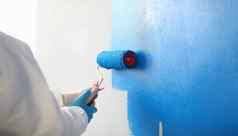 画家刷工具覆盖蓝色的颜色绘画墙