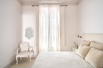 明亮的卧室室内舒适的床上米色亚麻干花床边表格日光照窗口窗帘