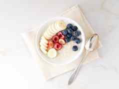 大碗美味的健康的燕麦片水果浆果早餐早....餐前视图白色大理石表格