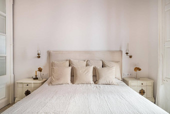 明亮的卧室室内舒适的床上米色亚麻干花床边表格复古的古董风格