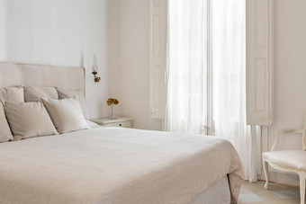 明亮的卧室室内舒适的床上米色亚麻干花床边表格复古的古董风格