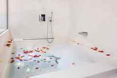 玫瑰花瓣把浴缸浪漫的浴室大气泡沫浴安排度蜜月夫妇