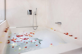 玫瑰花瓣把浴缸浪漫的浴室大气泡沫浴安排度蜜月夫妇