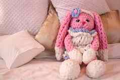 粉红色的兔子针织玩具坐在沙发动物用钩针编织amigurumi的地方文本