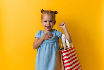 肖像高加索人美丽的快<strong>乐学</strong>前教育女孩微笑快乐的持有纸板袋孤立的橙色黄色的工作室背景幸福消费主义出售人购物概念