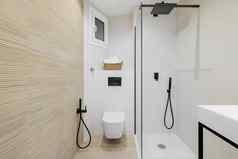 室内现代风格浴室白色米色颜色翻新公寓淋浴区厕所。。。黑色的水龙头毛巾平铺的地板上墙