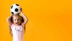 真实的可爱的微笑学前教育女孩经典黑色的白色足球球相机黄色的背景孩子玩足球t恤短裤体育运动冠军团队概念