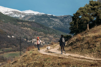 夫妇徒步旅行者背包狗走美丽的区域雪山森林蓝色的天空概念活跃的休息