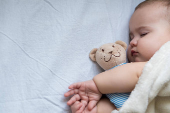 童年护理母亲健康概念关闭和平平静婴儿蹒跚学步的婴儿女孩睡眠休息深La2铺设拥抱泰迪熊玩具软温暖的毯子关闭眼睛大床上