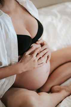 怀孕了女人坐在床上黑色的好持有手肚子