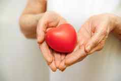 祖母女人手持有红色的心医疗保健爱器官捐赠正念幸福家庭保险企业社会责任概念世界心一天世界健康一天国家器官捐赠一天