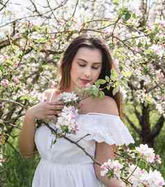 年轻的高加索人女人享受开花苹果树