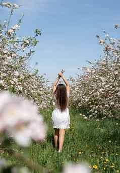 年轻的高加索人女人享受开花苹果树