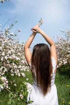 年轻的高加索人女人享受开花苹果树