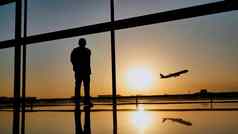 轮廓旅游的家伙看起飞飞机站机场窗口日落晚上旅行概念人机场